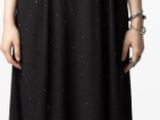 La femme porte une robe noire et des bottes noires.