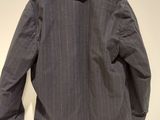 grey pinstripe jacket hanging on a hanger on a white wall