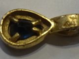 an image of a close up of a gold ring with a blue stone