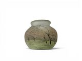 a vase that is sitting on the ground with trees in the background