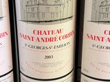 three bottles of red wine are lined up on a shelf