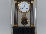 une petite horloge sous un dôme de verre sur une table