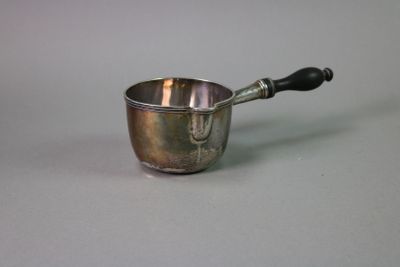 a small silver cup with a black handle on a table