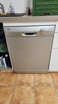 un lave-vaisselle blanc dans une cuisine au sol carrelé