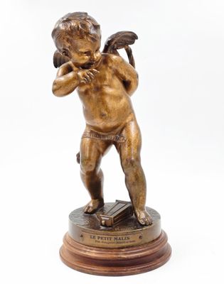 an antique bronze statue of a cupid holding a book on a wooden base
