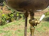 a brass water faucet that is on a pole