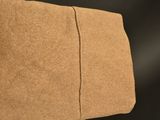 the back of a brown couch with a brown pillow on it