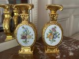 two gold vases sitting on a table with a mirror in the background