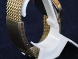 a close up of a gold and white watch on a black surface