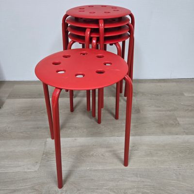 quatre tabourets rouges posés sur un parquet en bois massif