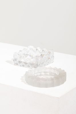 un objet en verre posé sur une surface blanche, sur laquelle se projette son ombre