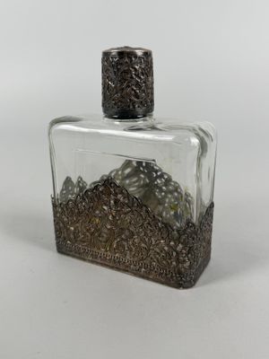 a small glass bottle with a metal decoration on it