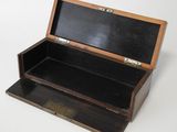 a small wooden box with a black lid on a white surface