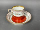 an orange and white cup and saucer sitting on top of a table