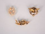 two gold brooches and a brooch on a white surface