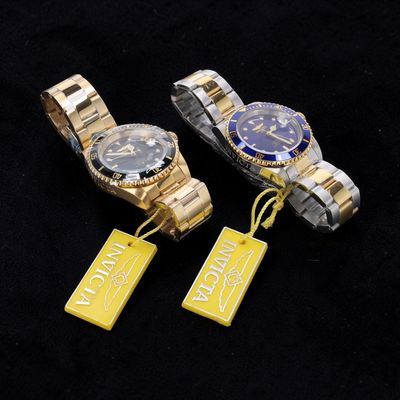 three different watches with tags attached to them on a black surface