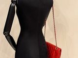 a mannequin with a red purse on a stand
