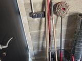 two brooms, a mop and a mop holder on the floor