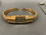 gold bracelet with a roman numeral on it and a pair of earrings