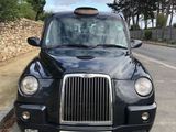 black cab parked on the side of the road in front of a stone wall