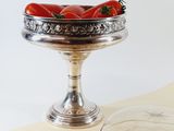 a bowl of tomatoes sitting on a table next to a glass bowl