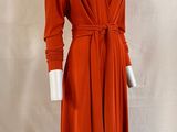an orange dress on a mannequin stand with a white mannequin behind it