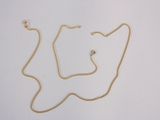 un collier en or dont la chaîne a été coupée en deux et qui repose sur une surface blanche
