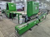 une image représentant une machine verte dans une usine, avec un tapis roulant