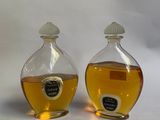 Deux bouteilles de miel sont posées l'une à côté de l'autre sur une surface blanche