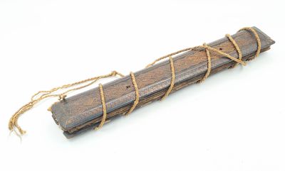 bâton en bois entouré d'une corde, posé sur une surface blanche