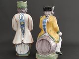 two figurines of men with hats and a drum