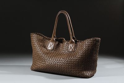 un gros plan d'un sac tissé marron posé sur une surface blanche