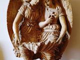 une statue représentant un ange tenant un enfant dans ses bras, posée sur une table