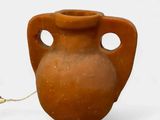 a brown vase with holes in it on a white surface