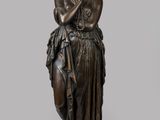 une statue en bronze d'une femme tenant un oiseau sur un piédestal