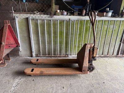 une palette en bois posée devant une clôture métallique
