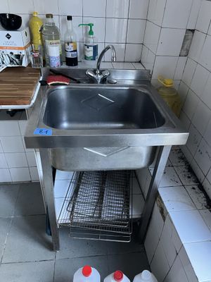 un évier dans un coin de la cuisine, avec de nombreuses bouteilles posées sur le plan de travail