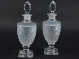 deux vases en verre transparent, surmontés d'un couvercle transparent, posés sur une surface noire