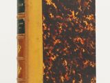 an old book with a brown cover sitting on top of a white table