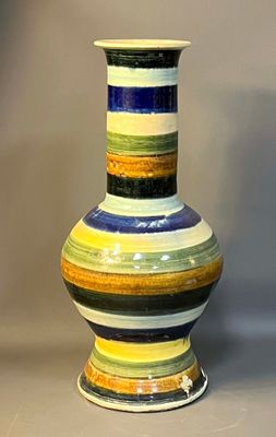 a multicolored vase sitting on a gray surface