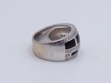 silver ring with black and white stones on it on a white surface
