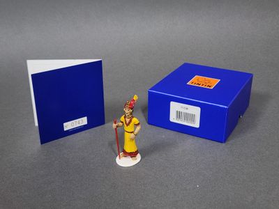 une petite figurine représentant une femme en robe jaune, à côté d'une boîte bleue