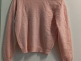 un pull rose accroché au mur à côté d'un miroir