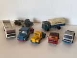 Plusieurs camions miniatures sont alignés sur une surface blanche
