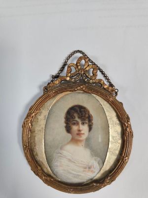 an old picture of a woman in a white dress is hanging on a wall