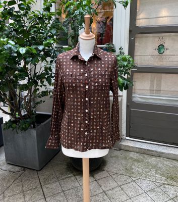 une chemise marron posée sur un mannequin devant un immeuble
