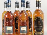 six bottles of whiskey lined up in a row on a white surface