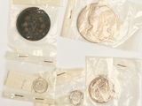 plusieurs pièces de monnaie et une pièce dans un sachet, posées sur une surface blanche
