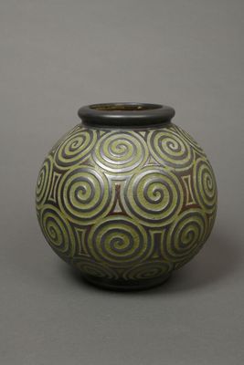 a green and black vase sitting on a gray surface
