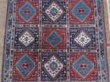 a red, blue and white rug on a wooden floor